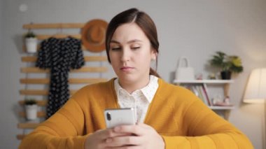 Çevrimiçi öğrenme, video çağrısı, uzaktan eğitim konsepti. Yatak odasında telefonu olan genç bir kadın kameraya bakıyor ve web kamerasından konuşuyor. Not alıyor ve telefona yazıyor.