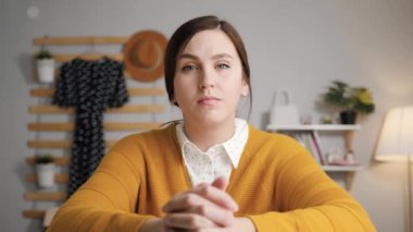Çevrimiçi öğrenme, online toplantı, uzaktan eğitim konsepti. Yatak odasındaki sarı kazaklı genç çekici kadın masaya oturup kameraya bakıyor ve videodaki konuşmacıyı dikkatle dinliyor.