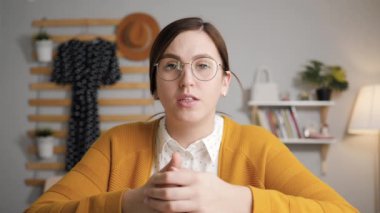 Çevrimiçi öğrenme, konferans, uzaktan eğitim, online ders konsepti. Yatak odasında gözlüklü genç ve çekici bir öğretmen ya da öğrenci kameraya bakıyor ve biriyle konuşuyor.