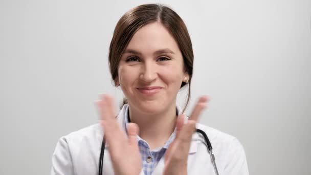 Un applauso del dottore. Ritratto di donna sorridente positiva medico su sfondo grigio guardando la fotocamera e battendo le palme felicemente. Rallentatore — Video Stock