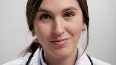 Doktor sadece duyguları düşün. Gri arka plandaki kendine güvenen kadın doktor kameraya bakıyor ve parmağıyla şakağına vuruyor ve kamerayı işaret ediyor. Yavaş çekim