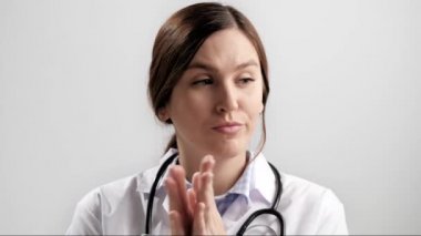 Doktor alaycı alkış. Gri arka plandaki kasvetli şüpheci kadın doktor kameraya bakıyor ve sahte alkış yaratmak için avuçlarını isteksizce çırpıyor. Yavaş çekim