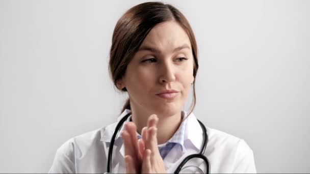 Doctor sarcastic applause. Gloomy skeptical woman doctor on gray background looking at camera and reluctantly claps her palms to create fake applause. Slow motion — Stock Video