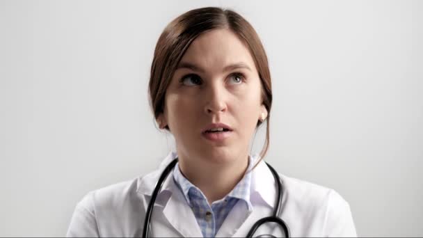 Doctor FACEPALM. Mujer doctora asombrada sobre fondo gris mirando a la cámara y cubre su cara con su palma de la mano expresando su desconcierto. Movimiento lento — Vídeo de stock