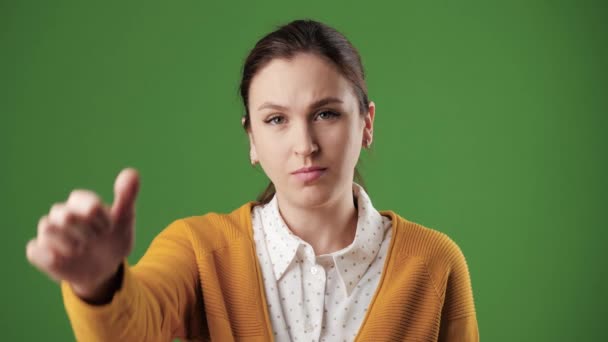 Frau Daumen runter. Stirnrunzeln ernste Frau auf Chroma-Schlüssel Hintergrund blickt in die Kamera und zeigt ihren Daumen nach unten. Zeitlupe — Stockvideo