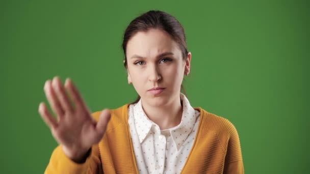 Femme paume ARRÊT. Femme sérieuse fronçant les sourcils sur fond chromatique en regardant la caméra lève la main et montre sa paume signalant ARRÊT. Mouvement lent — Video