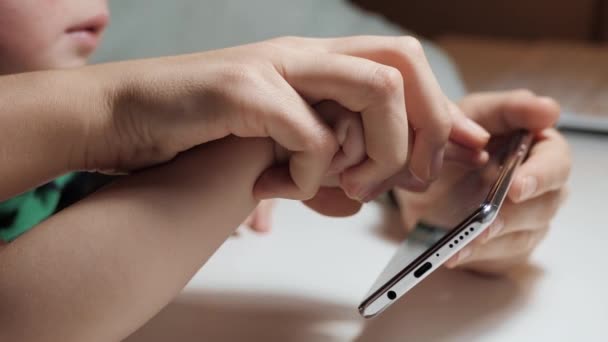 Dětská ruka ťuká na obrazovku telefonu. Detailní záběr dětské ruky, kterou drží dospělá ruka a tiskne na displej chytrého telefonu. Detailní záběr a zpomalení — Stock video