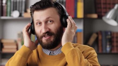 Kulaklıklı adam konuşuyor ve gülüyor. Pozitif sakallı erkek öğretmen ya da kulaklıklı iş adamı biriyle konuşuyor ve gülüyor. Yavaş çekim