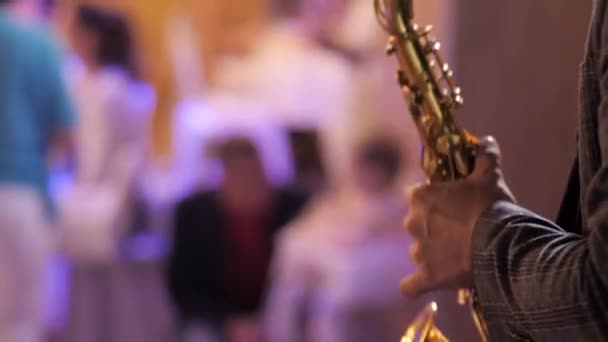 Saxofonista. Mãos masculinas estão segurando saxofone, saxofone jogador empurrar botões saxofone e toca melodia no salão de banquetes brilhante. Close-up — Vídeo de Stock