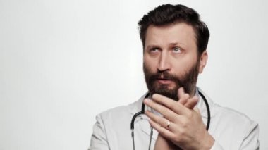 Doktor alaycı alkış. Beyaz arka plandaki kasvetli, kuşkucu sakallı doktor portresi kameraya bakıyor ve sahte alkış yaratmak için isteksizce avuçlarını çırpıyor.