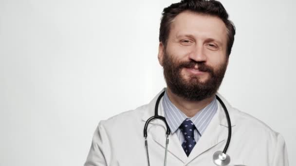 닥터 엄지로 들어. 흰색 배경에 긍정적 인 미소를 짓고 있는 의사가 카메라를 보고 있고 엄지손가락 이 위를 보고 있는 모습 — 비디오