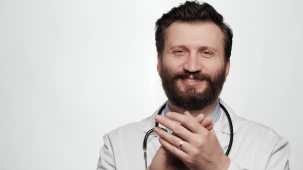 Doktor potlesk. Portrét pohledný vousatý pozitivní úsměv a smích muž lékař na bílém pozadí při pohledu na kameru a tleskání jeho dlaně šťastně — Stock video