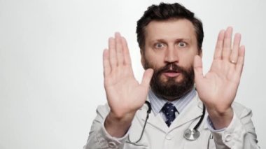Doktor hayır diyor, anlaşmazlık, dur. Beyaz arka planda korkmuş endişeli bir doktor kameraya bakıyor ve ellerini gergin bir şekilde sallamaya başlıyor, hayır-hayır-hayır diye bağırıyor.