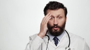 Şok oldum doktor. Beyaz arka planda kameraya bakan doktor adam şaşkınlık ve yanlış anlaşılma yaşıyor.