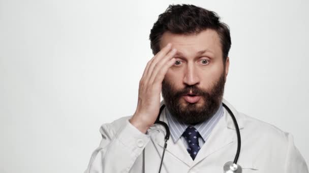 Doctor sorprendido. Hombre médico sobre fondo blanco mirando a la cámara está en la pérdida perplejidad y malentendido, emoción facepalm — Vídeo de stock