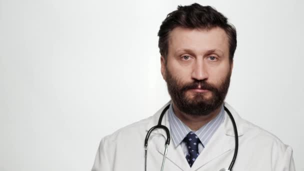 Il dottore pensa solo alle emozioni dei gesti. Positivo medico uomo su sfondo bianco guardando la fotocamera e toccando il dito sulla tempia, suggerisce di pensare bene — Video Stock