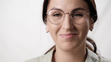 Beyaz arka planda gözlüklü, gülümseyen kadın. Beyaz arka planda gözlük takan, güler yüzlü beyaz kadın portresi. Yakın plan.