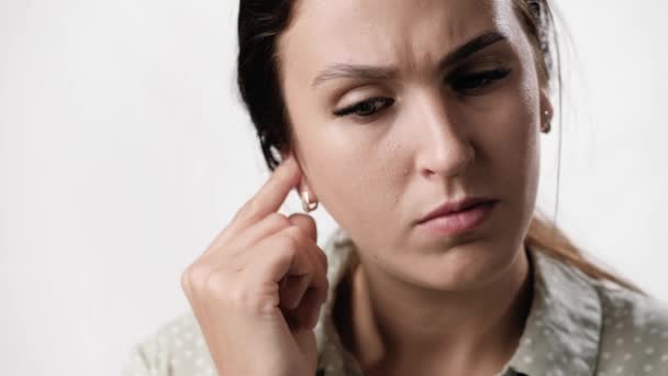 Itching in ear. Puzzled woman on white background with emotions of irritation scratches her ear with finger. Close-up and slow motion — Stock Video