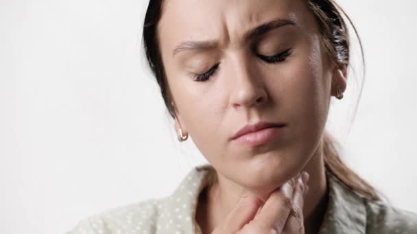 Sore throat. Suffering woman on white background touches her neck with her hand feeling sore throat. Close-up and slow-motion — Stock Video