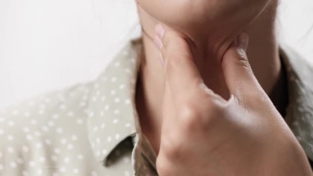 Halsont. Kvinnlig hand på vit bakgrund vidrör kvinnlig hals med ont i halsen. Närbild och slow motion — Stockvideo
