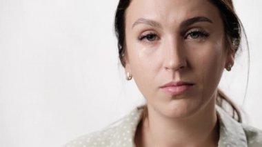 Kadın ağlıyor, ağlıyor. Beyaz arka planda yüzü ağlayan kadın kameraya bakıyor. Yakın çekim ve yavaş çekim