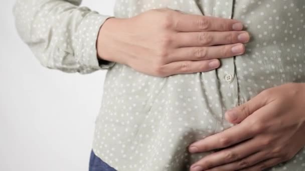 Στομαχόπονος. Θηλυκά χέρια αγγίζουν ανήσυχα την κοιλιά σε λευκό φόντο. Κοντινό πλάνο και αργή κίνηση — Αρχείο Βίντεο