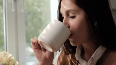 Kadın içiyor ve kahvenin tadını çıkarıyor. Kahve ya da çay içen kadın zevkten zevk alır ve pencereden dışarı bakar. Yakın çekim ve yavaş çekim