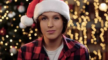 Kadın kameraya bakıp gülümsüyor ve hava öpücüğü yolluyor. Mutlu Noeller ve mutlu yıllar konsepti. Yakın plan.