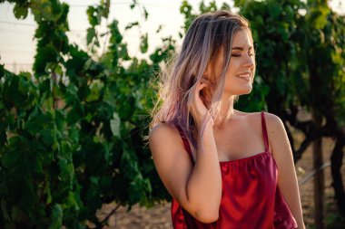 Yaz mevsiminde üzüm bağlarında kırmızı elbiseli genç bayan portresi. Harika şaraphane bölgesinde degustation turunun tadını çıkarıyor..
