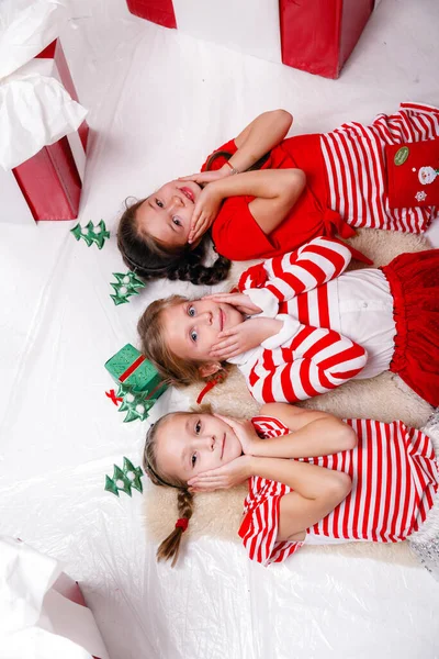 在红色大礼物的背景下 滑稽的小女孩们穿着圣诞服装和朋友们在一起 快乐假期 友谊和童年的理念和概念 — 图库照片
