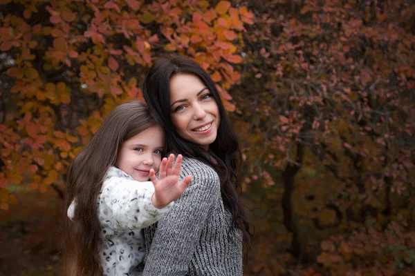 Happy family on an autumn walk. Mother and daughter walking in the park and enjoying the beautiful autumn nature.