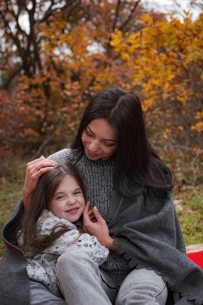 Happy family on an autumn walk. Mother and daughter walking in the park and enjoying the beautiful autumn nature.