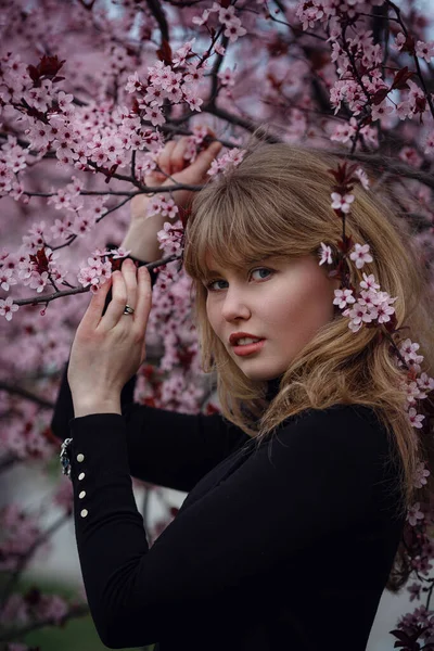 Outdoor fashion photo of a beautiful young lady in a pink cherry blossom garden. like a sakura in Japan.