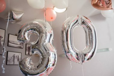 Doğum günü için pembe balonlarla süslenmiş bir oda, 30 yıl için gümüş balonlar.