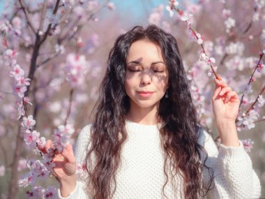 Çiçek açan kiraz ağacının yanında güzel bir genç kadın. Kişisel bakım, sağlık ve mutluluk fikri ve konsepti