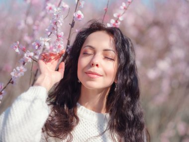 Çiçek açan kiraz ağacının yanında güzel bir genç kadın. Kişisel bakım, sağlık ve mutluluk fikri ve konsepti