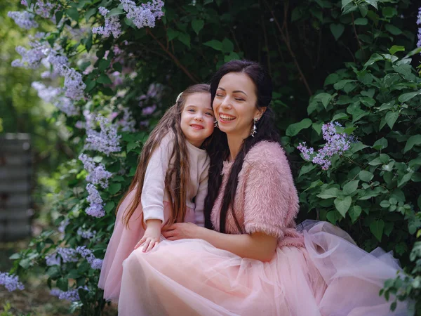在春天的紫丁香花园里 穿着漂亮的粉色连衣裙 在户外玩得很开心的女人 妈妈和孩子笑着拥抱着 家庭假期和团聚 母亲节快乐 — 图库照片