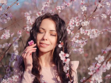Çiçek açan kiraz ağacının yanında güzel bir genç kadın. Yenilenme fikri ve konsepti, kişisel bakım ve mutluluk