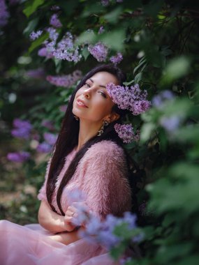 Bahar bahçesinde yürüyen ve leylak kokusunun tadını çıkaran güzel bir genç kadın. Aromaterapi ve Bahar Konsepti