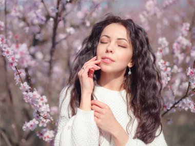 Çiçek açan kiraz ağacının yanında güzel bir genç kadın. Kişisel bakım, sağlık ve mutluluk fikri ve konsepti