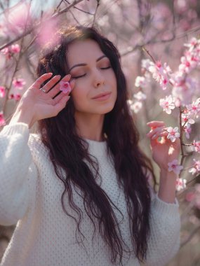 Çiçek açan kiraz ağacının yanında güzel bir genç kadın. Kişisel bakım, sağlık ve mutluluk fikri ve konsepti