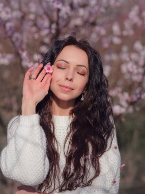 Çiçek açan kiraz ağacının yanında güzel bir genç kadın. Yenilenme fikri ve konsepti, sağlık ve mutluluk