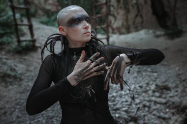 Siyah uzun elbiseli gizemli kel kadın. Tapınağın yakınındaki gotik pagan kadın ve putlar. Vampir karanlık, gizemli bir ormanda yürüyor..