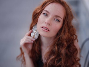 Siyah takım elbiseli kızıl, genç bir kadın bahar kasabasında yürüyor. Avrupa 'da sokak kafesinde poz veriyor