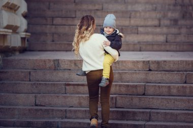 Anne ve oğlu güneşli bir sonbahar gününde dışarıda yürüyorlar. Sonbahar tarzı giyinmiş bir aile. Birlikte mutluyuz.