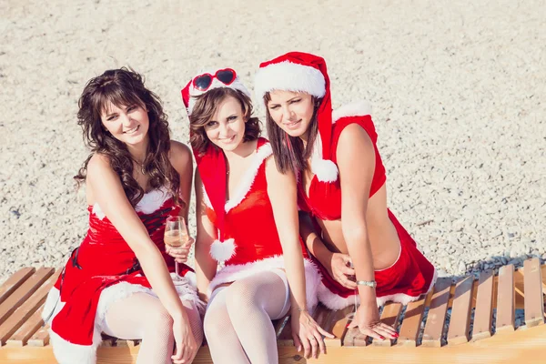 Amigos felizes em chapéus de Pai Natal na praia. férias de Natal — Fotografia de Stock