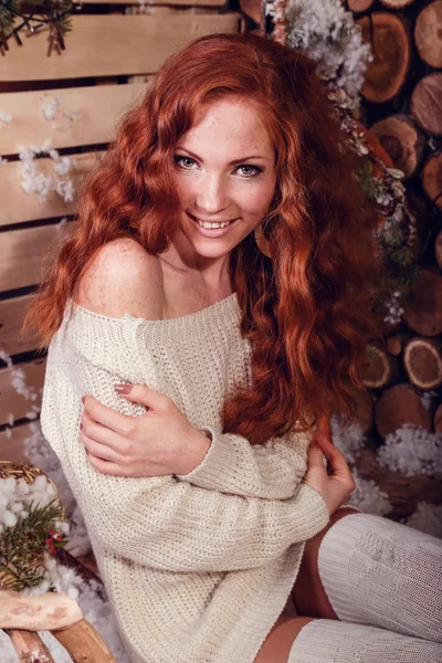 attractive young woman in a winter fashion shot wearing a white woolen sweater and a knitted socks