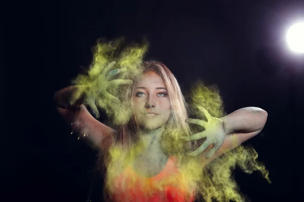 Girl with colored powder exploding around her and into the background. — Stockfoto
