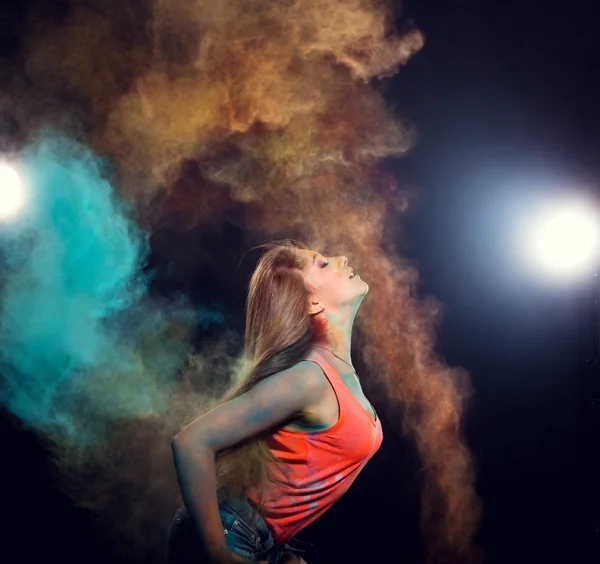 Girl with colored powder exploding around her and into the background. — Stockfoto