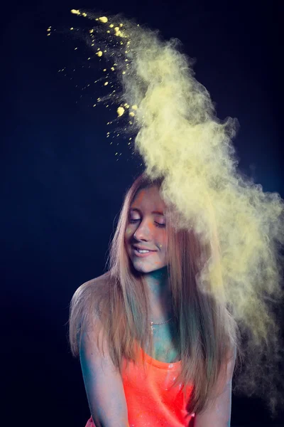 Ragazza con polvere colorata che esplode intorno a lei e sullo sfondo . — Foto Stock